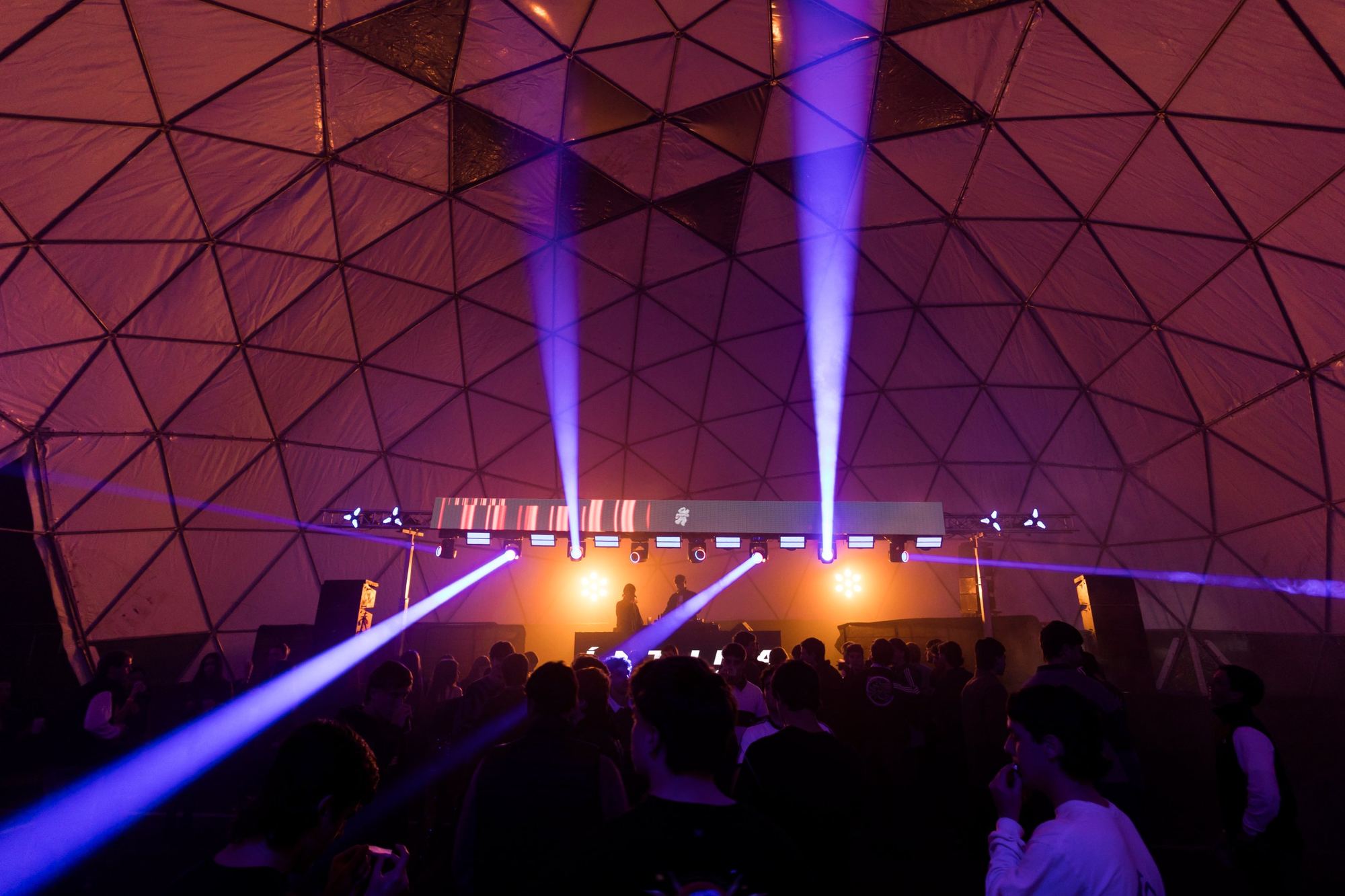 Pista llena bajo la cúpula con haces de luz violetas